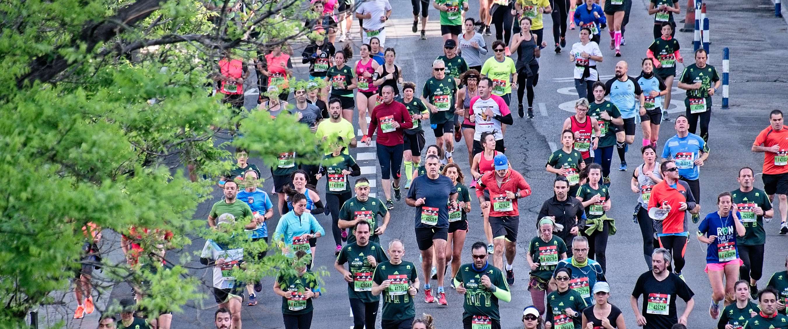 Marathonlopers in diverse sportkleding rennen samen over een stedelijk parcours, gezien van bovenaf