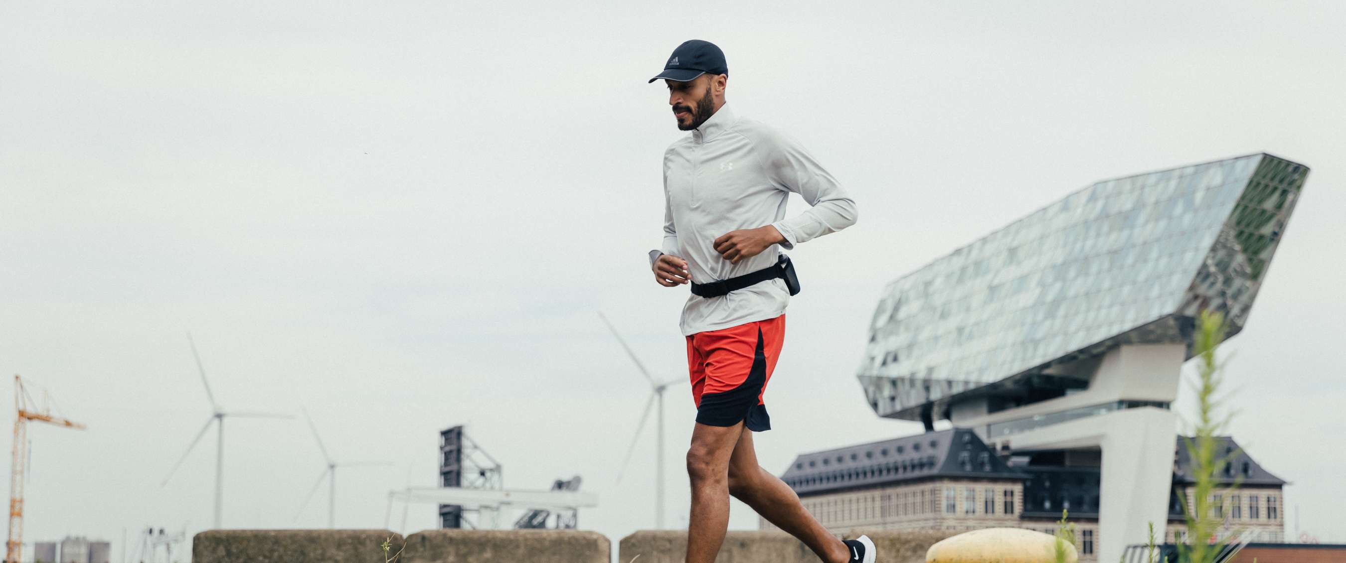 Hardloper traint alleen langs het water in een stedelijke omgeving met moderne gebouwen op de achtergrond