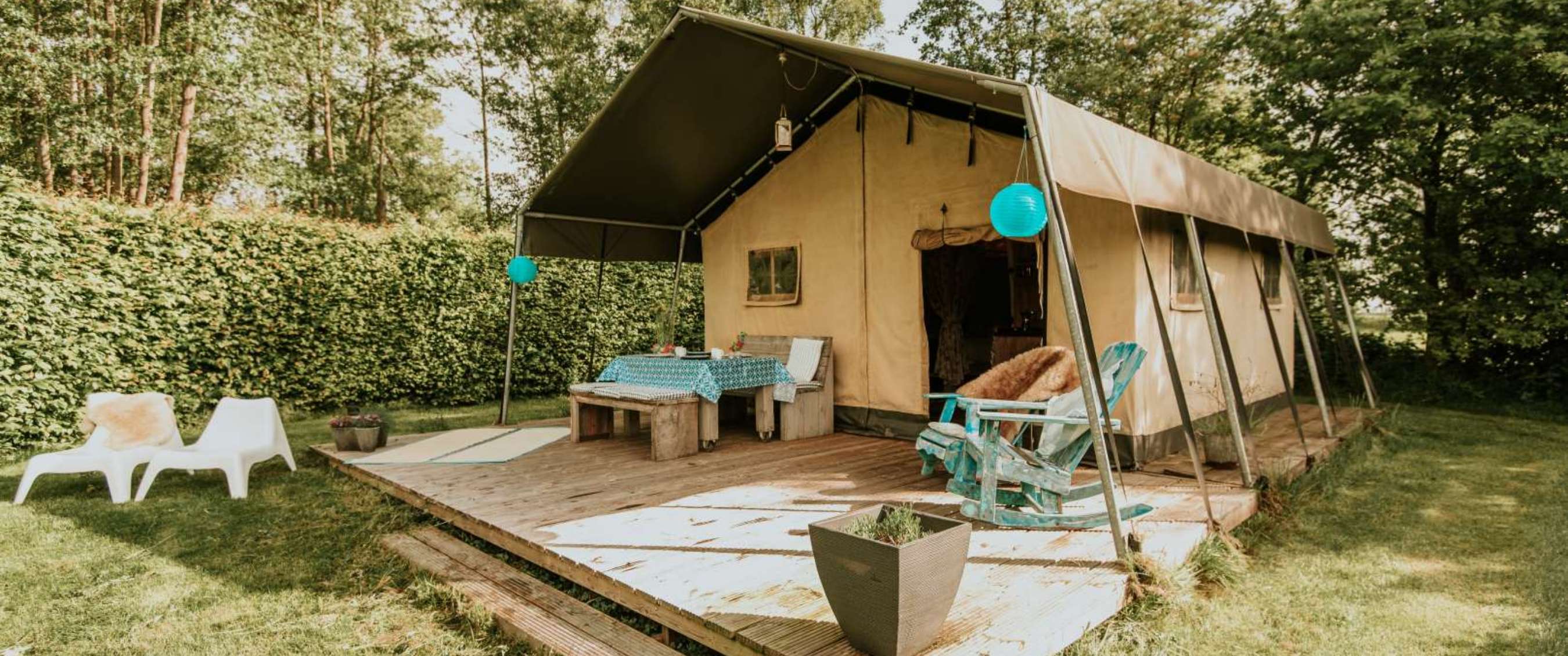 Safaritent met houten terras, tafel, stoelen en blauwe lampions
