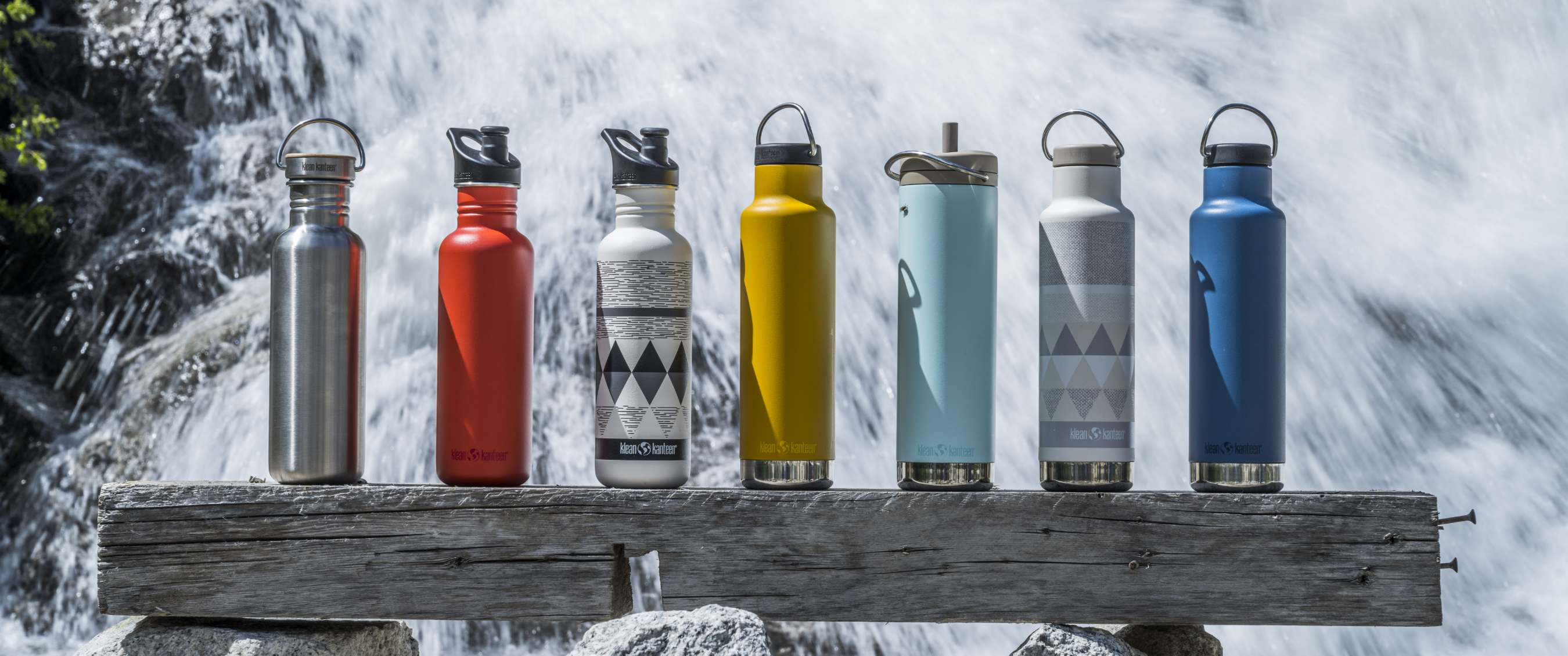 Drinkflessen in verschillende kleuren op een balk met stromend water op de achtergrond