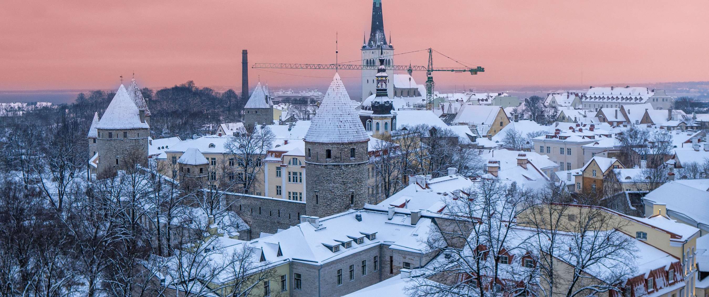 Besneeuwde middeleeuwse torens en een skyline met historische gebouwen in pastel.