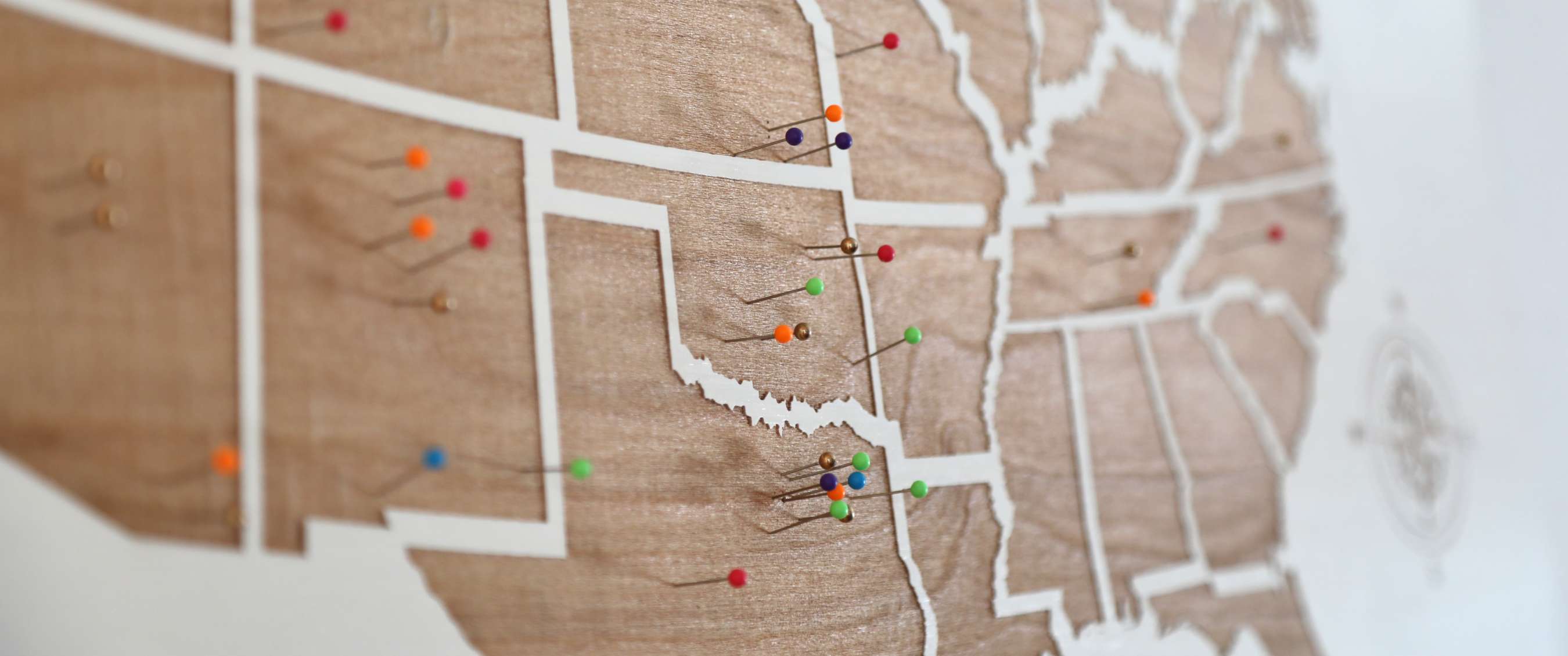 Houten wereldkaart met witte landsgrenzen en gekleurde punaises