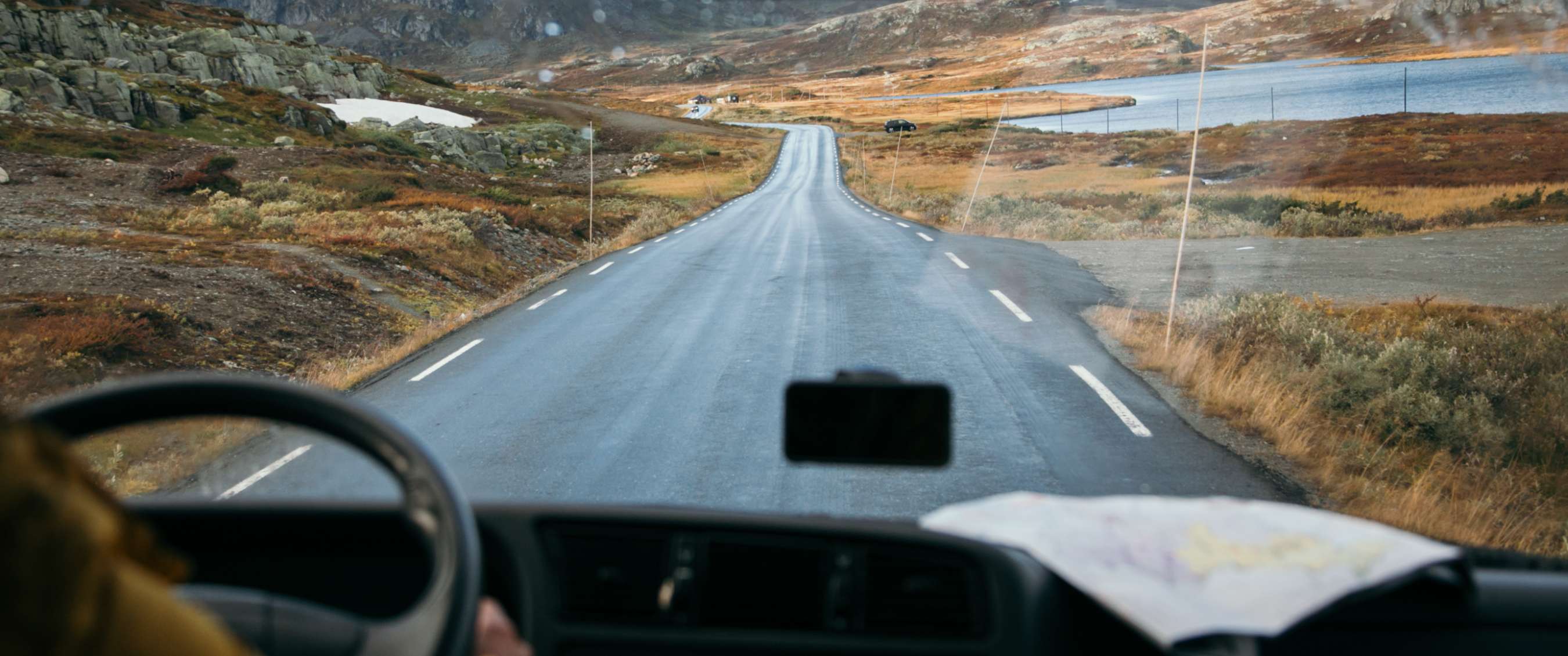 Zicht vanuit voertuig op lege weg door ruig berglandschap