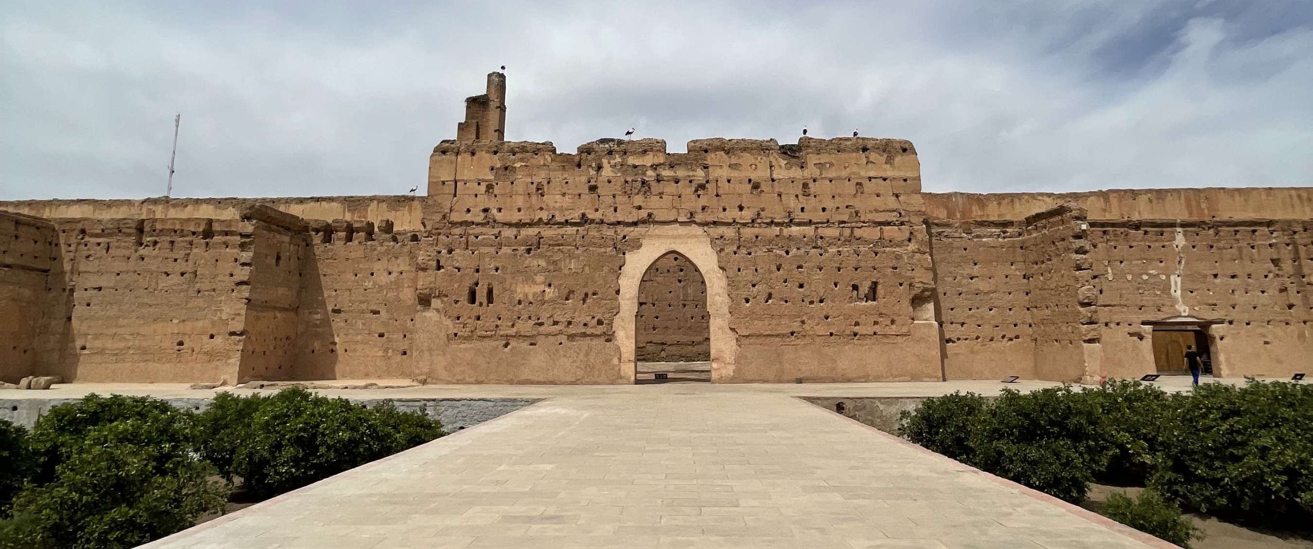 Grote historische vestingmuur met centrale boogpoort aan het einde van een brede stenen doorgang.