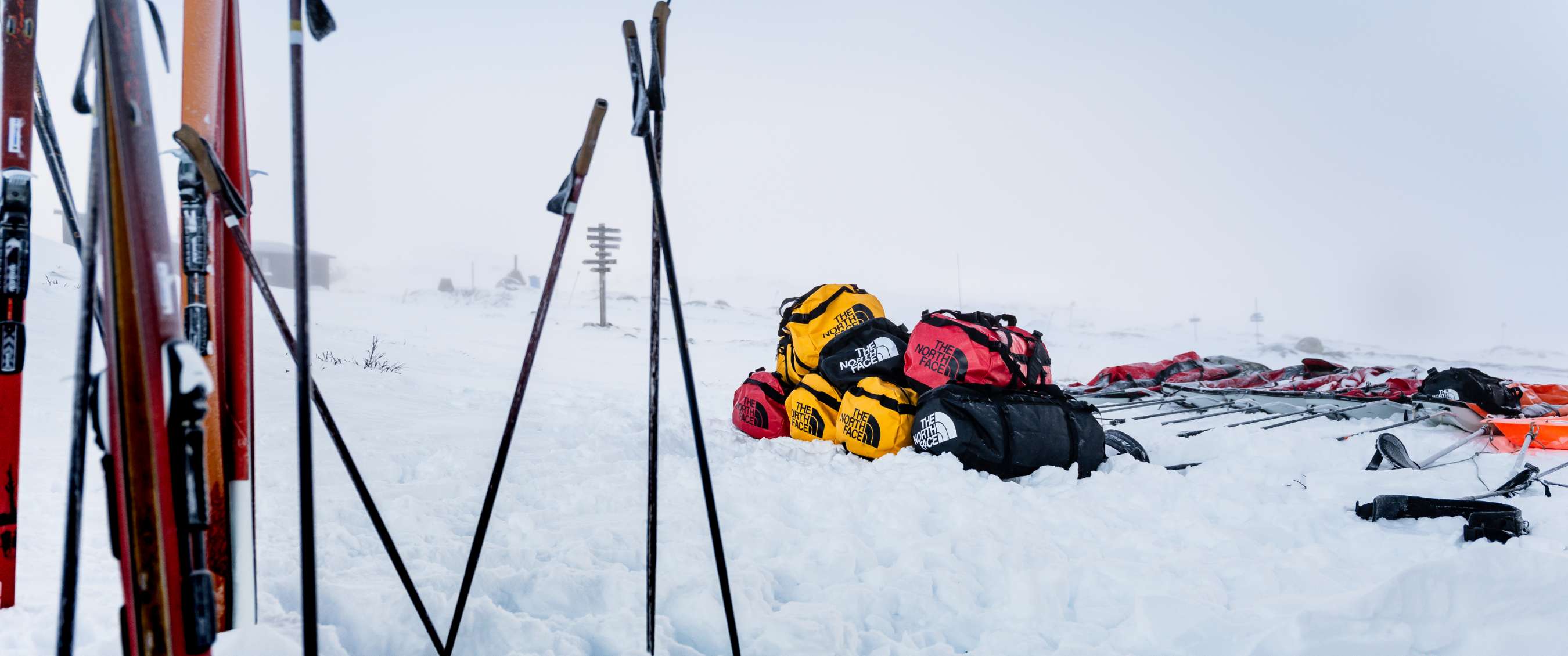 Gekleurde reistassen met The North Face-logo verzameld in besneeuwd landschap.