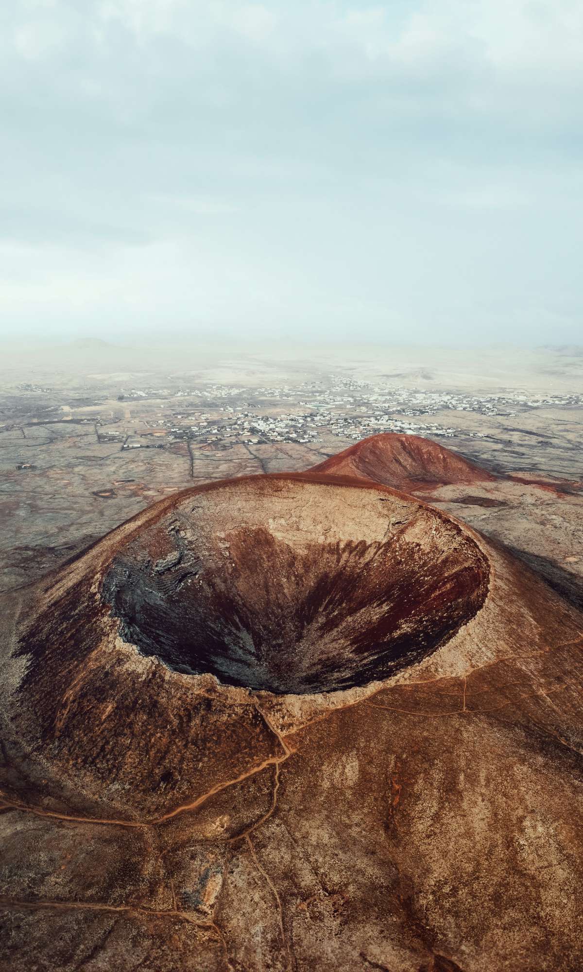 Luchtbeeld van een grote vulkaankrater in een droog landschap.