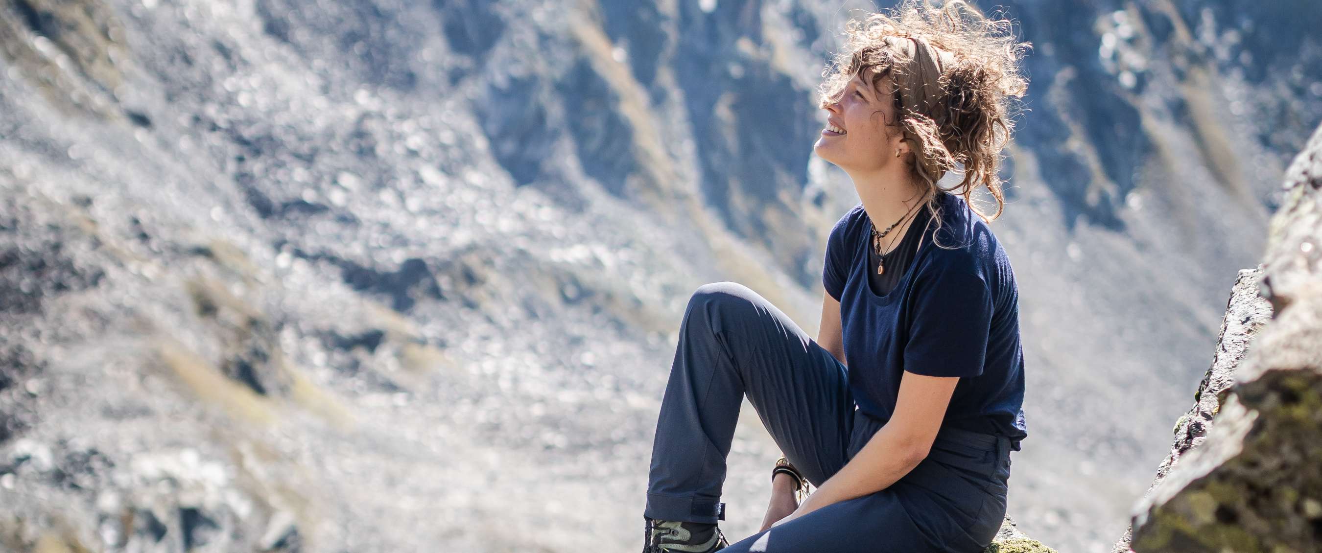 Persoon in wandelkleding rust op een rotshelling in de bergen.