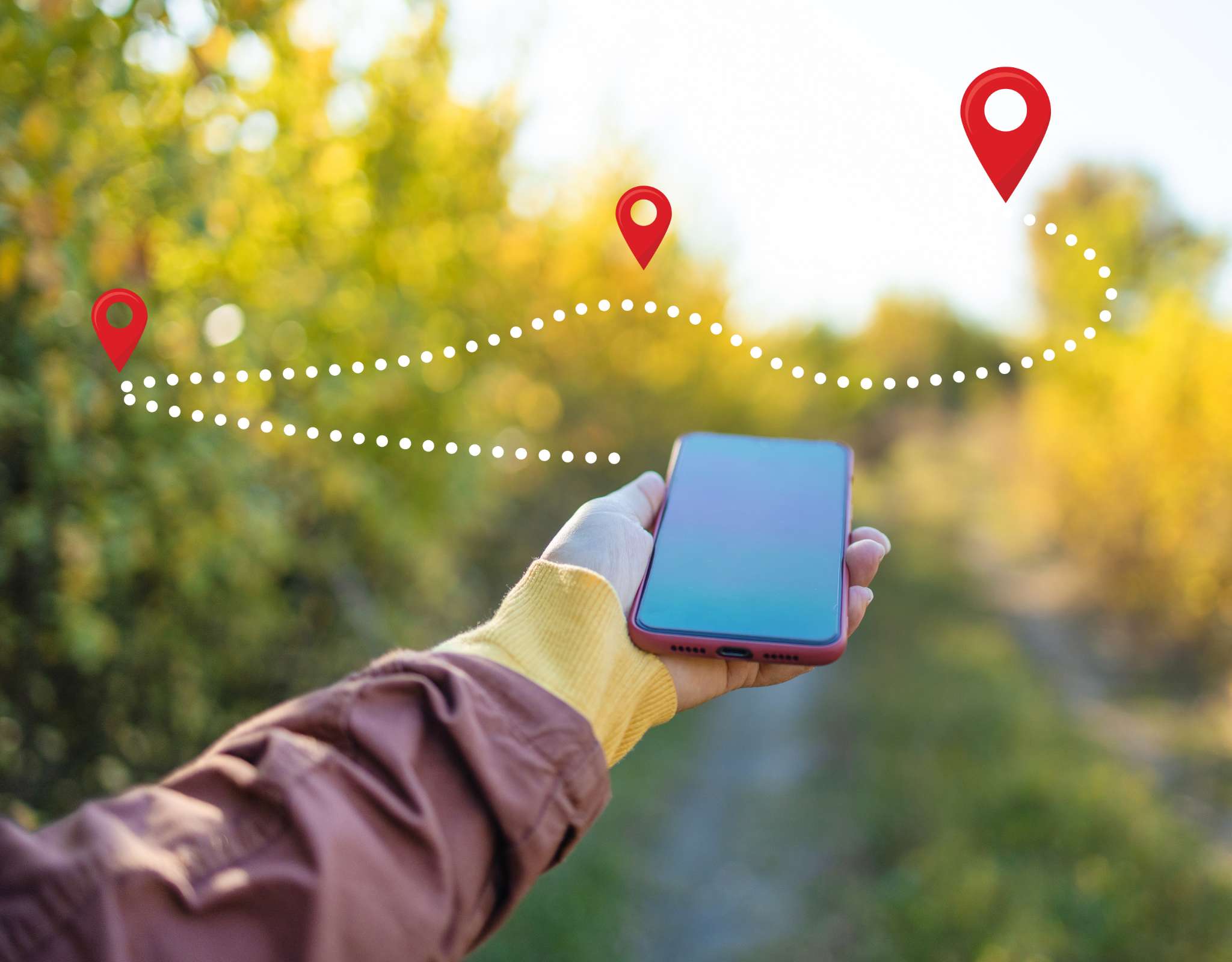 Smartphone in hand met visuele gps-route en locatiepinnen boven een bosrijk pad