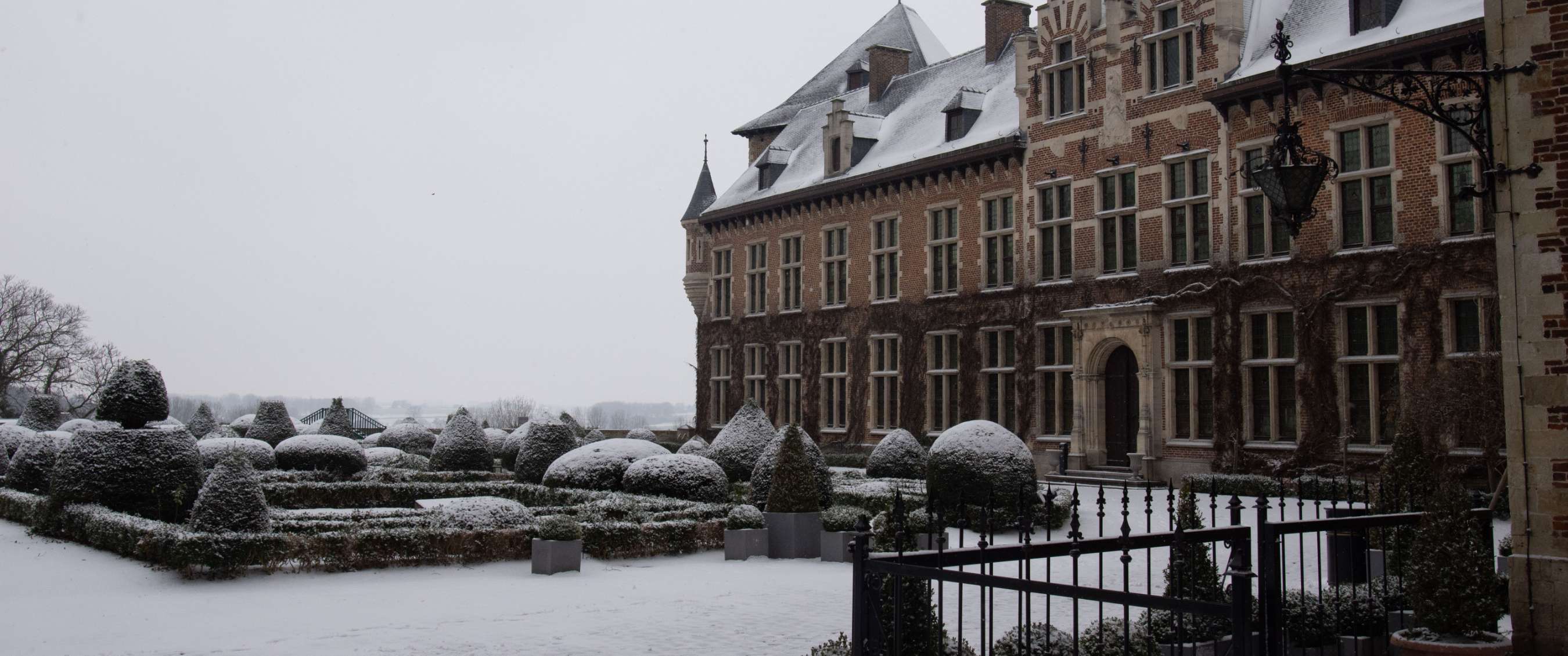 Sneeuwbedekte kasteeltuin naast een monumentaal gebouw
