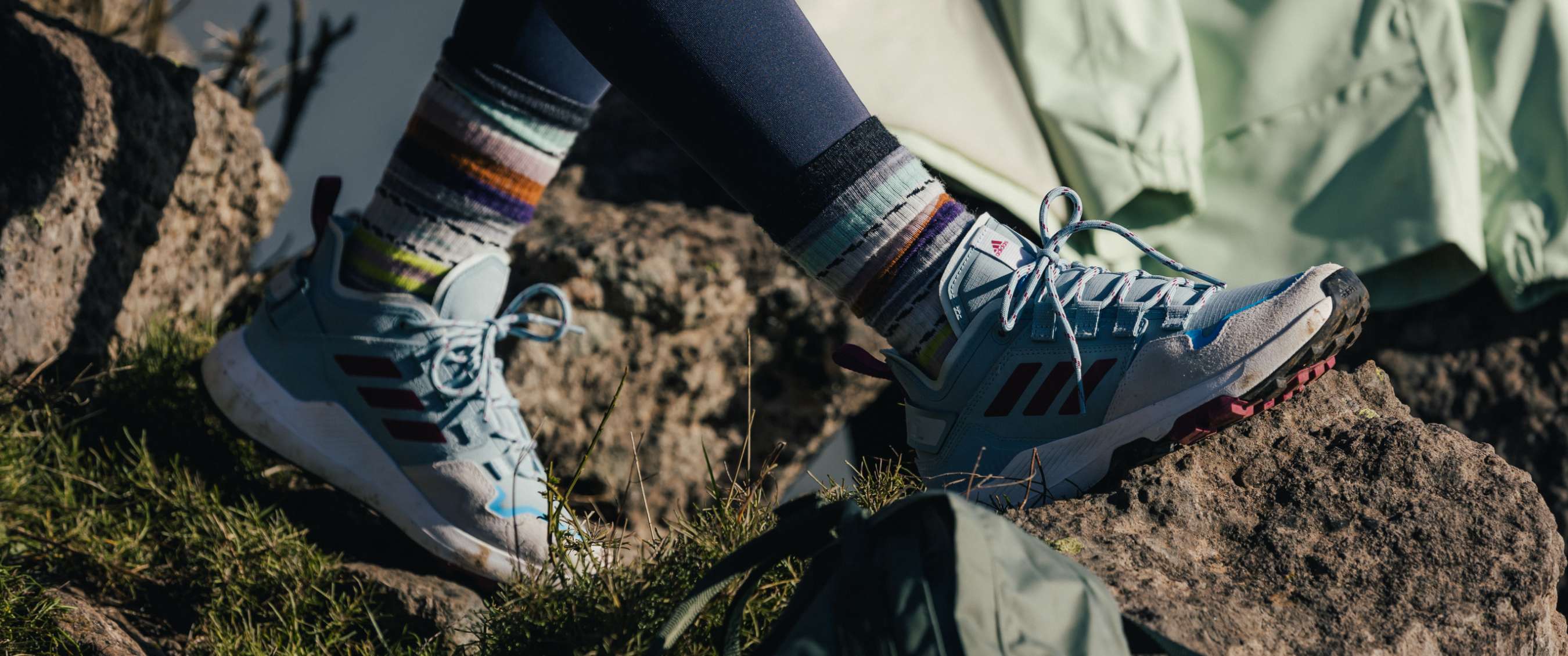 Close-up van wandelschoenen met gestreepte sokken op rotsachtige ondergrond.