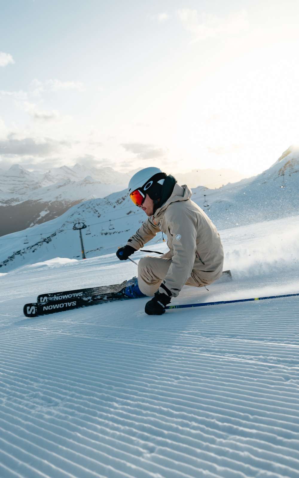 Skiër in beige skikleding maakt een scherpe bocht op een geprepareerde piste.